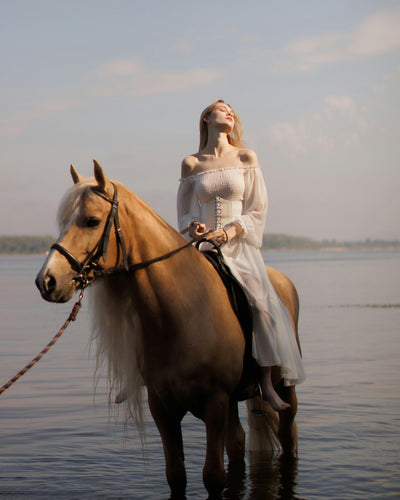Woman riding a horse along a Bali beach at sunset